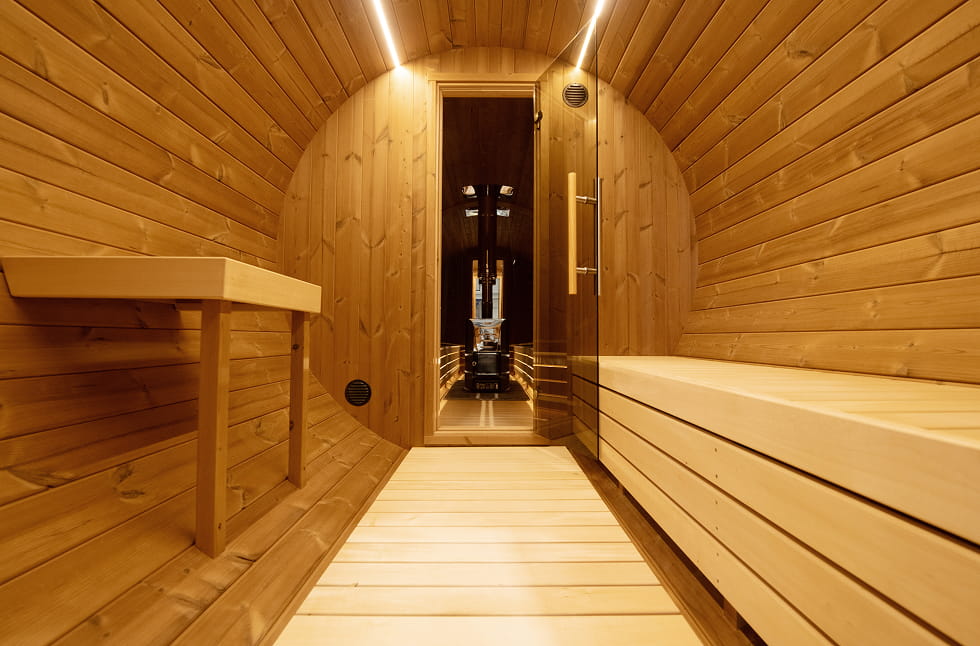 Wooden barrel sauna interior with a bench , LED lightind, glass door and table.