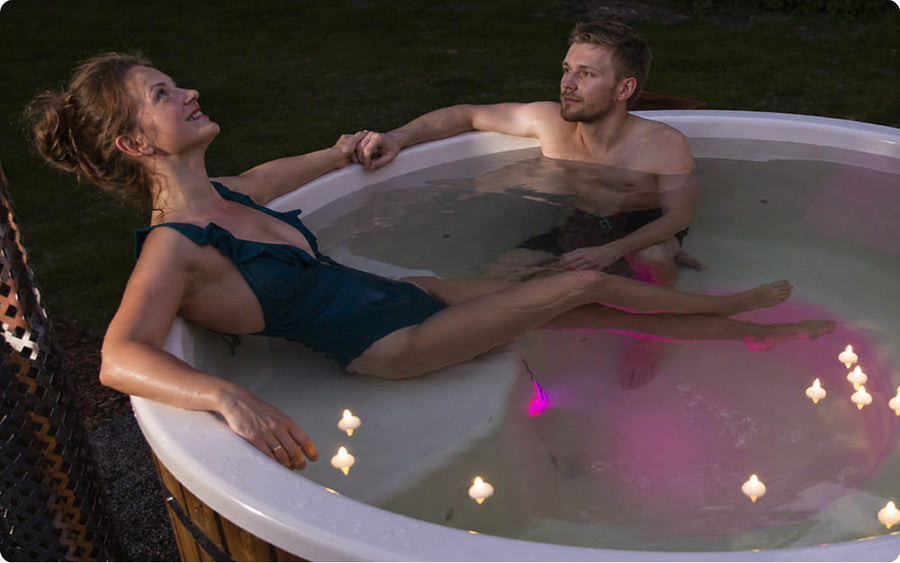 Two people in a hot tub with candles and lights.