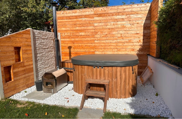 Auf der Terrasse befindet sich ein quadratischer, überdachter Hot Tub mit Filterkasten, Standardtreppe und einem Außenofen mit Kamin.