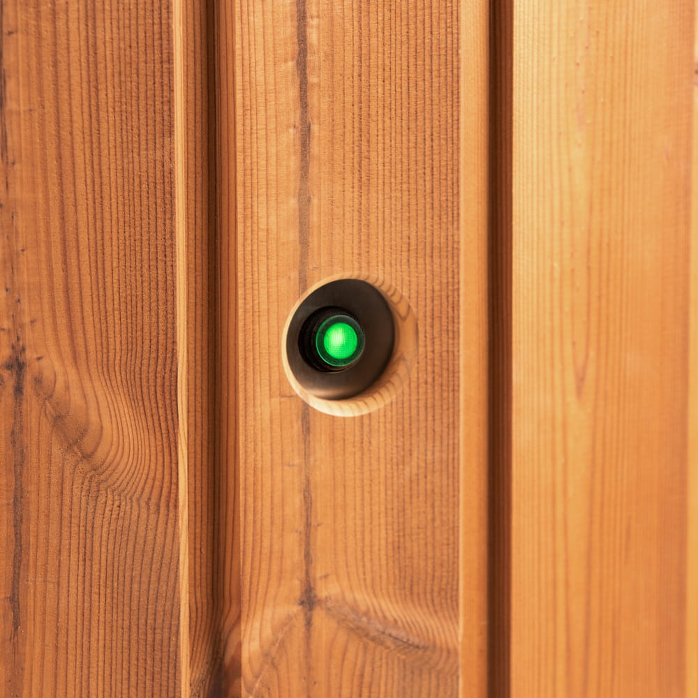 Wooden wall of hot tub's filter with a green light on a black button