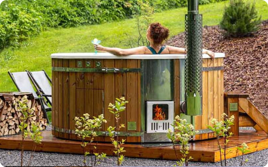 Woman relaxing in a hot tub with a wooden deck and outdoor setting