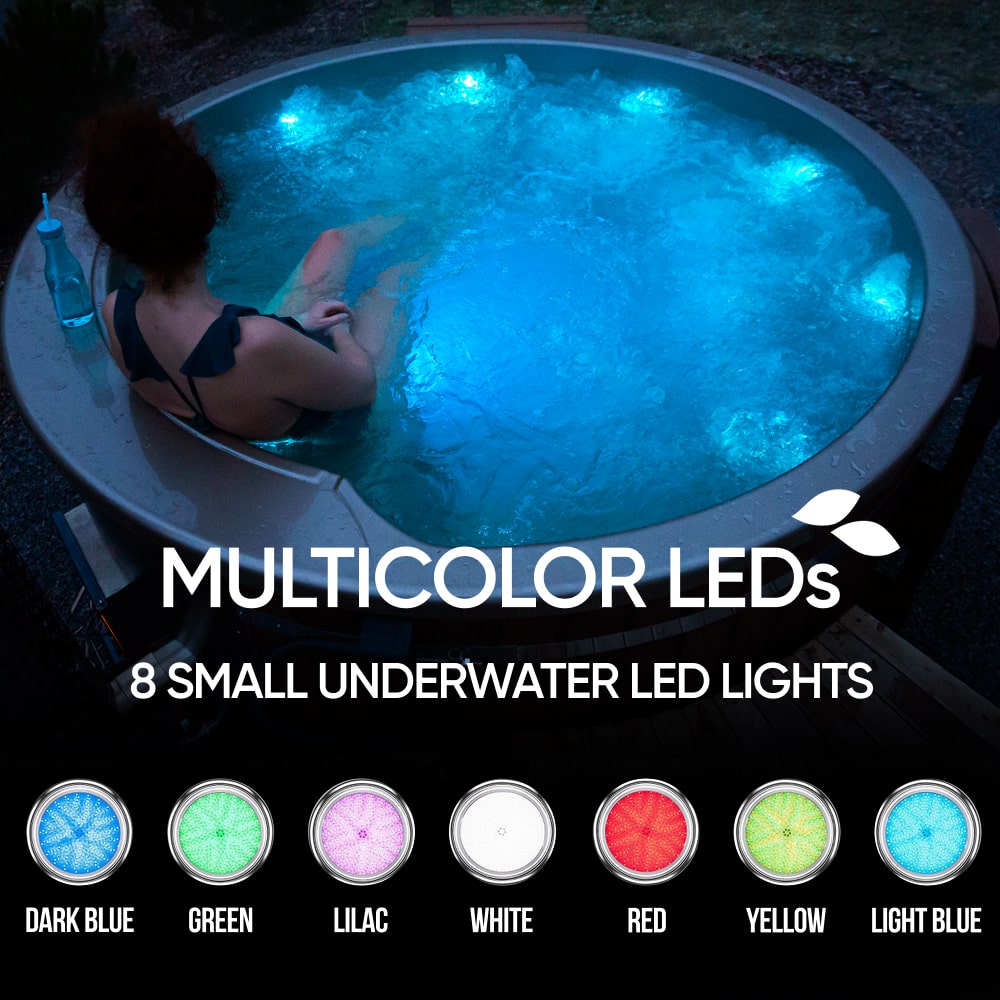 Evening view of 4-6 seater wood fired hot tub with multicolor underwater LED lights and bubbling water