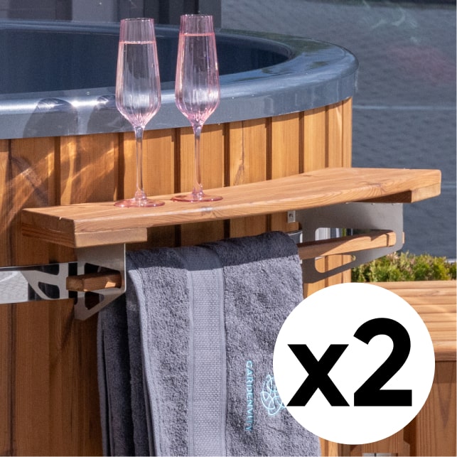Nahaufnahme eines externen Holzregals mit Handtuchhalter, das an der Seite des holzbefeuerten hot tub montiert ist; im 2er-Set abgebildet, mit Gläsern.