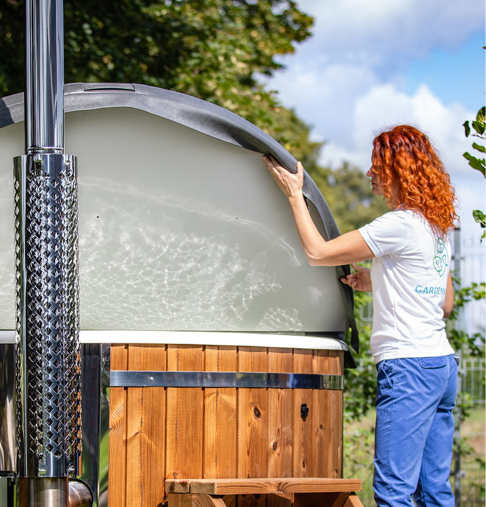 Eine Frau deckt an einem sonnigen Tag ihren Whirlpool ab.