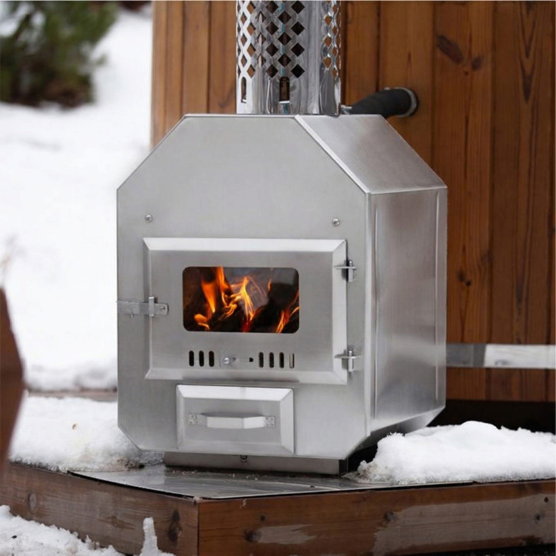 External wood-fired stove with visible fire in a snowy outdoor setting