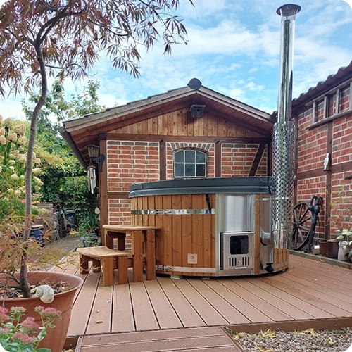 Wooden hot tub with metal exterior on a wooden deck outdoors.